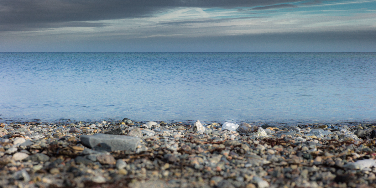 Ostseestrand - Steine - Wasser - Himmel