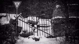 Das alte Eingangsportal vom Benther Berg Gasthaus. Verfallene Mauern und Treppen. Schnee auf den Stufen. Das alte Eisentor verrammelt mit einem Eisenrohr. Davor ein Schild Landschaftsschutzgebiet.